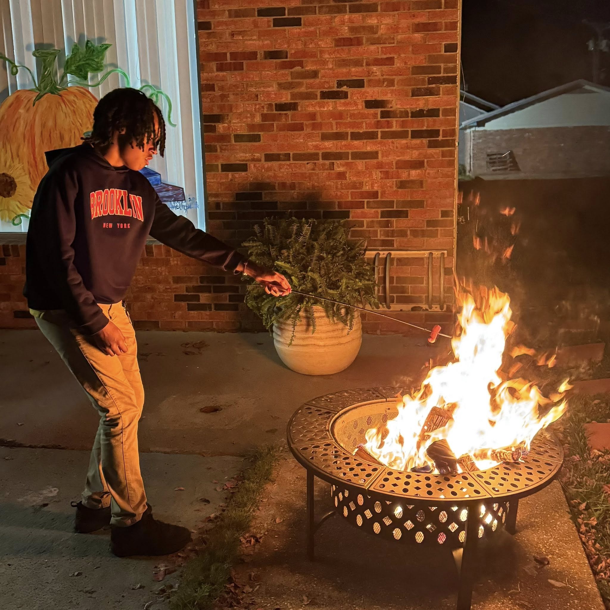 A kid roasting a hotdog over a firepit.